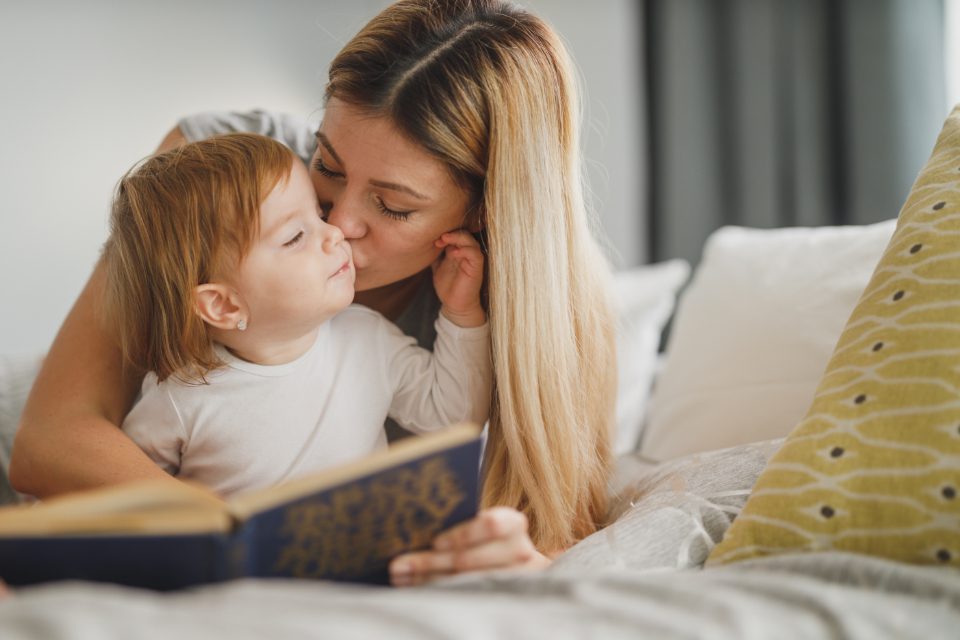 A mother tenderly holding her young child in soft window light.